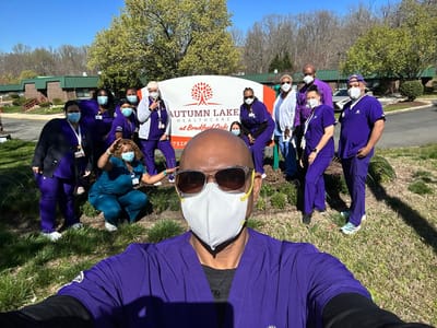 Staff members posing in front of the facility sign