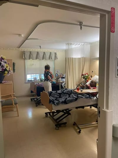 A resident receiving care in a room with staff present