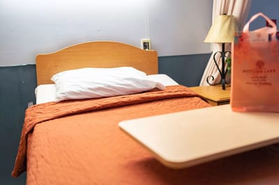 A resident room with an orange blanket and bedside table