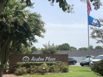 Exterior sign of Avalon Place with flags and landscaping