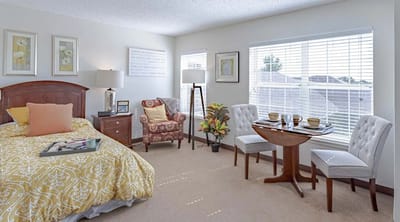 A cozy, well-furnished resident room with a bed and dining area