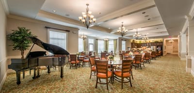 Bright dining room with piano and tables set for meals