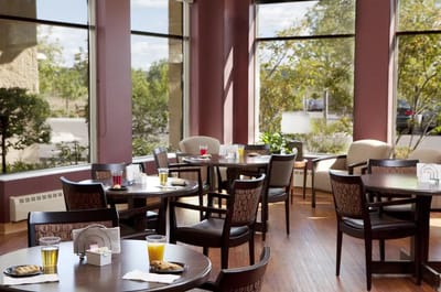 Dining room with tables and beverages near large windows