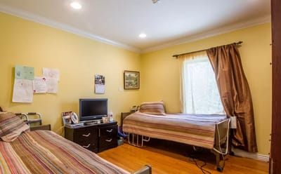 A shared resident room with two beds and a TV