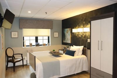 A well-furnished private resident room with a bed and chair