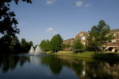 Scenic view of a pond with a fountain and the facility in the background