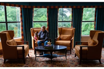 Resident sitting in a cozy lounge with a dog