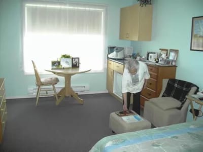 An elderly woman arranging items in her private room