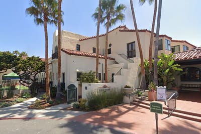 Exterior view of Casa de Mañana facility with palm trees
