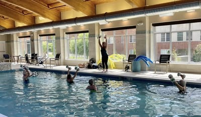 Residents participating in a water aerobics class in an indoor pool