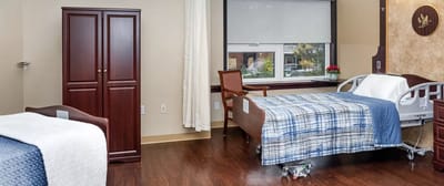 A bright, private resident room with a hospital bed and furniture