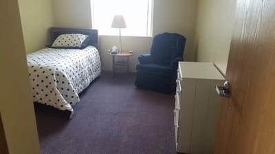 A private resident room with a bed and chair