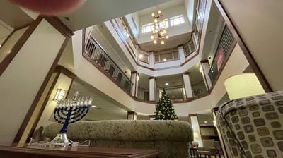 Interior view of a common area with a large chandelier and Christmas tree