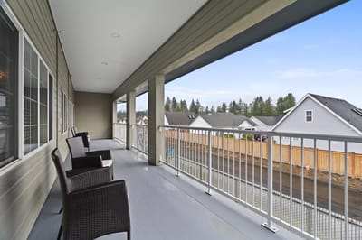 Covered balcony with outdoor chairs overlooking the neighborhood
