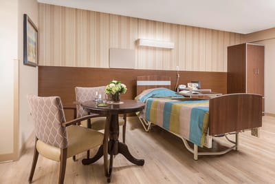 Bright private resident room with a bed and table