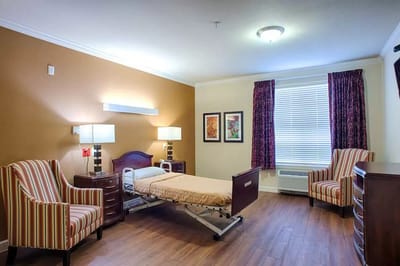 Cozy resident room with a hospital bed and armchairs