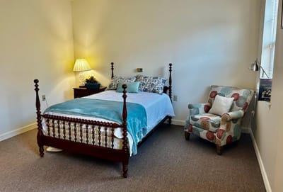 A cozy resident room with a bed and chair