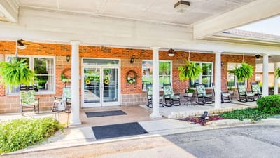 Entrance of Emerald Gardens Assisted Living with rocking chairs and greenery