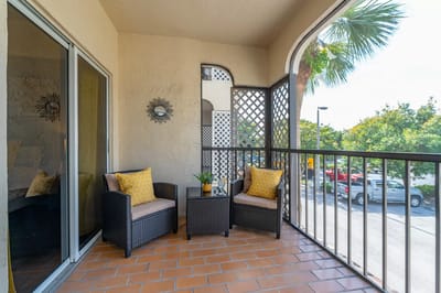 Balcony with seating and plants overlooking a parking lot