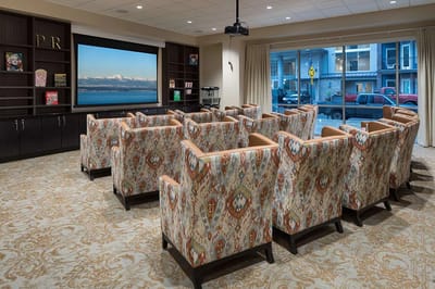 Interior view of a cozy common area with chairs and a projector