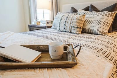 Cozy bedroom setup with a coffee cup and book on a tray