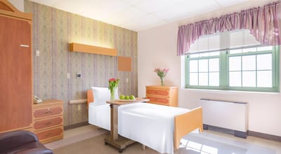 Cozy private room with a bed and flower arrangement