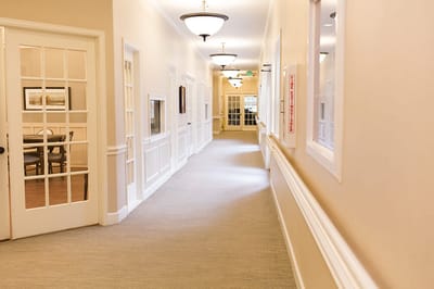 Well-lit corridor with seating area visible through a door
