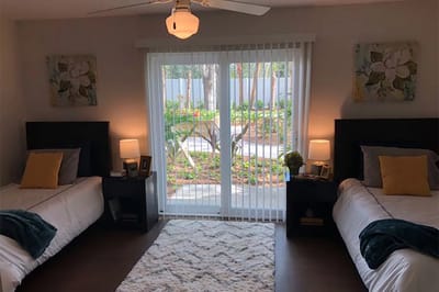 Bright resident room with two beds and a view of the garden