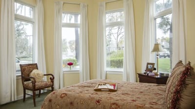 A cozy bedroom with windows and soft lighting