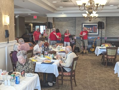 Residents enjoying a meal with live music in the dining room