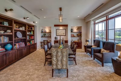 A well-decorated common area with a long table and chairs