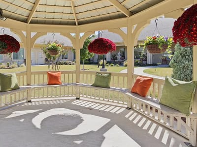 A gazebo with colorful hanging flowers and cushions