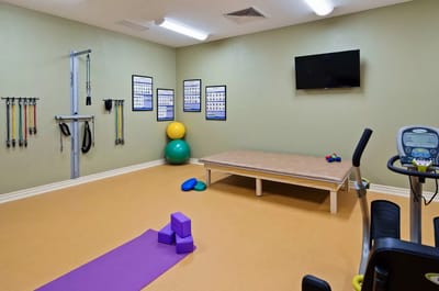 Physical therapy room with exercise equipment and mats