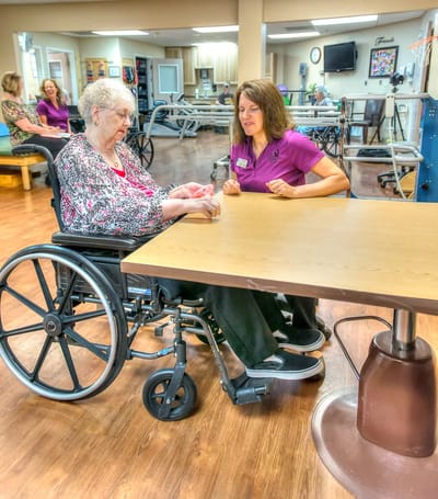 A resident and staff member engaged in a conversation in a therapy area