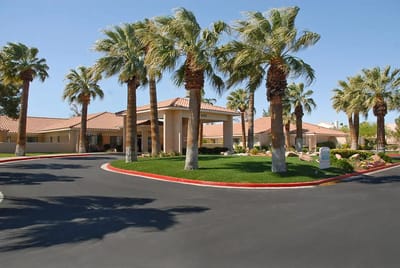 Entrance of a senior living facility surrounded by palm trees