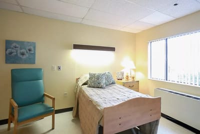 Interior view of a private resident room with a bed and chair