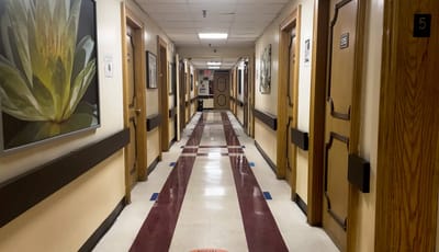 A hallway with doors and artwork in a nursing home