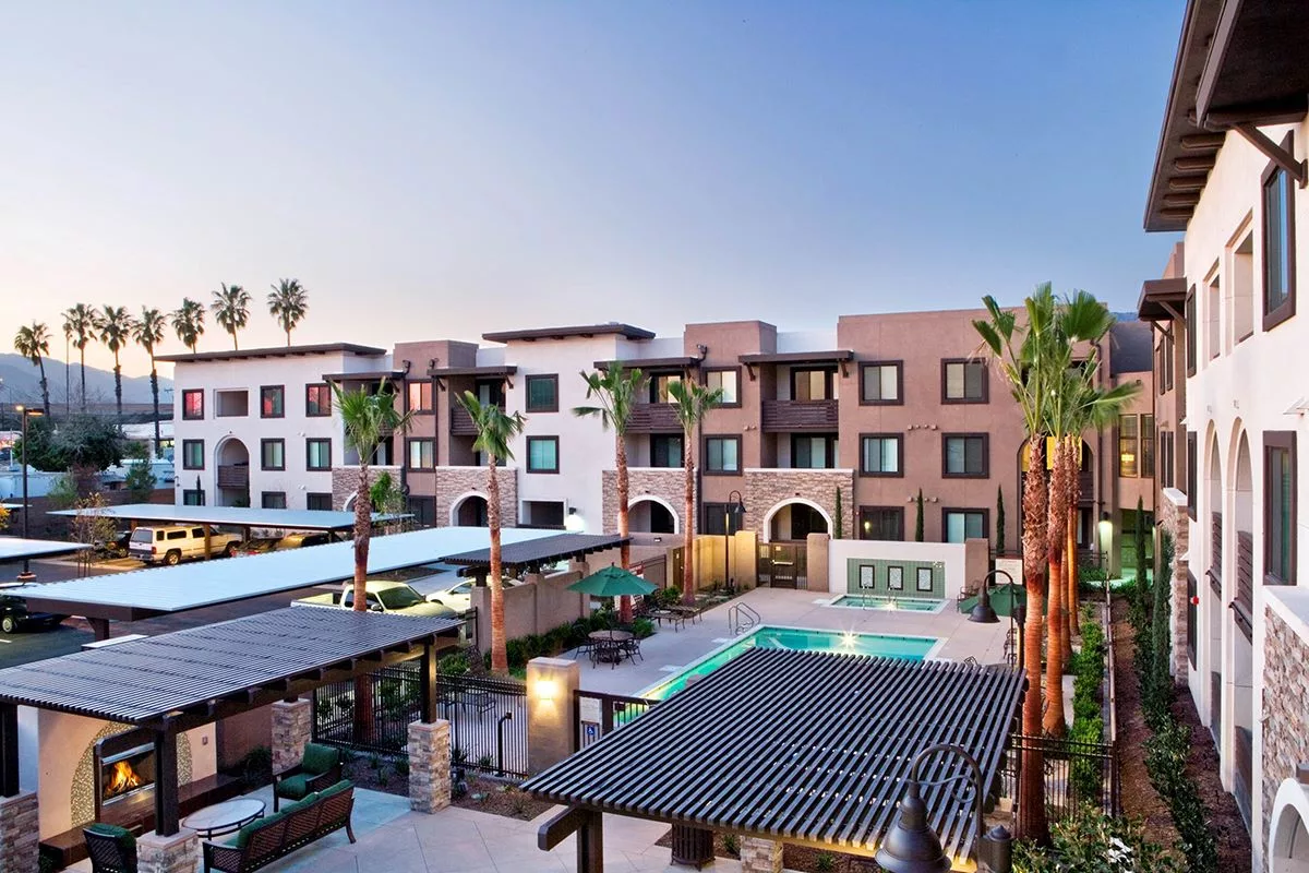 Exterior view of senior apartment complex with pool and palm trees