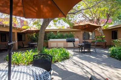 Sunny outdoor patio area with seating and grill
