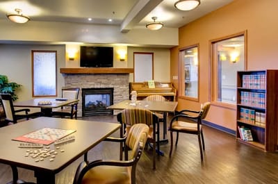 Bright activity room with tables and a fireplace