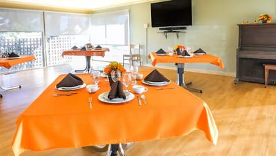 Dining room set up for a meal with orange tablecloths