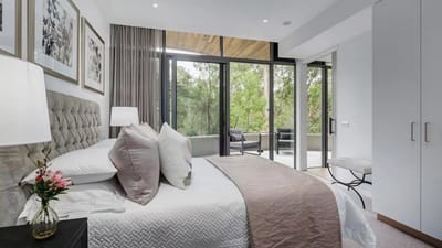 Bright, modern bedroom with large windows overlooking greenery
