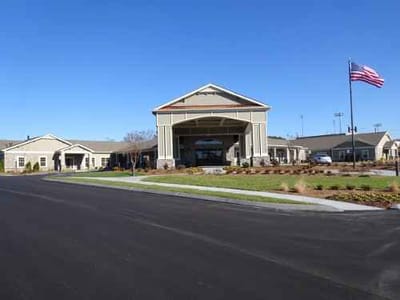 Facility exterior view with gardens and flag