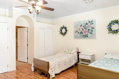 A bright resident room with two beds and floral decor