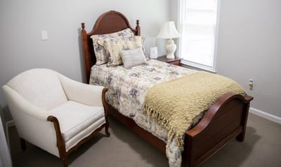 A private resident room with a bed and armchair