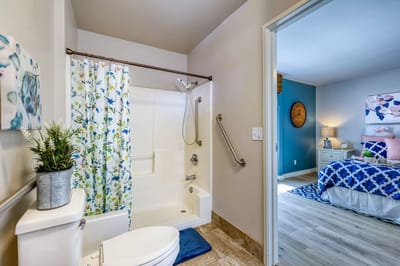 Brightly lit bathroom with floral shower curtain and blue accent wall