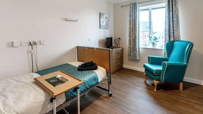 A private resident room with bed and chair