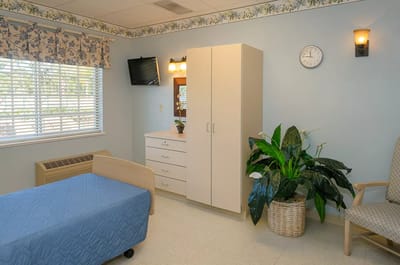 Well-lit resident room featuring a bed and dresser