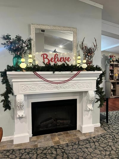 Christmas decor on a decorative mantle with a 'Believe' sign