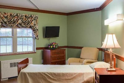 Cozy resident room with a bed, chair, and window